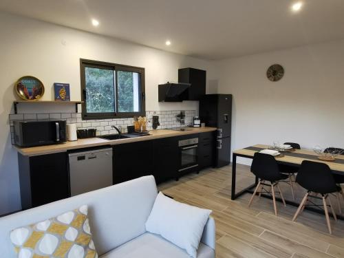 a kitchen and living room with a couch and a table at Appartement Jardin et Piscine Les anges du maquis location Corse-du-Sud in Conca