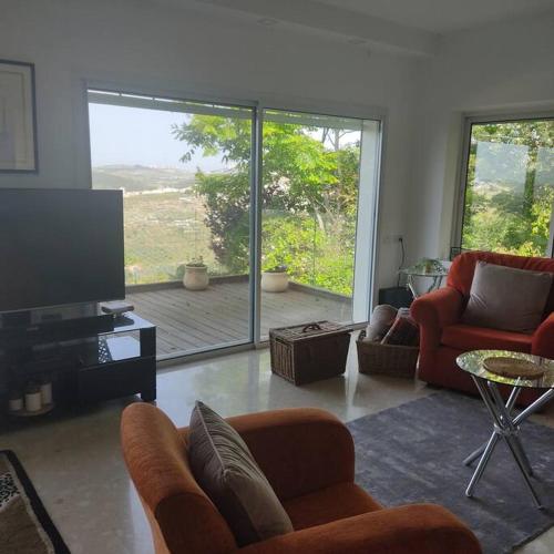 a living room with couches and a television and a large window at הבית על הגבעה in ‘Ilūṭ