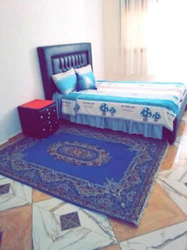 a bedroom with a bed and a rug on the floor at Blue meadow in Moulay Bousselham