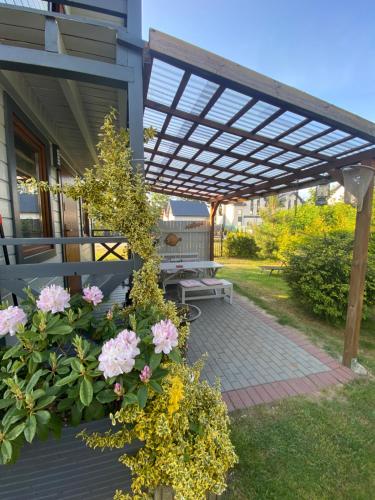 a pergola with a bench and flowers on a patio at Baltic Star in Władysławowo