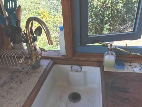 fregadero en una cocina con ventana en Secluded Shepherds Hut, with a view and hot tub en Ashburton