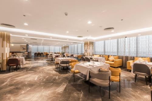 a restaurant with white tables and yellow chairs at Gewan White Beach Resort-New Alamein in Marsa Matruh
