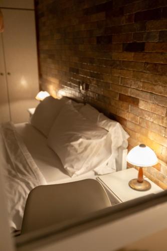 a bed with a brick wall and a table with a lamp at Αnastasia apartments in Mavrovoúnion