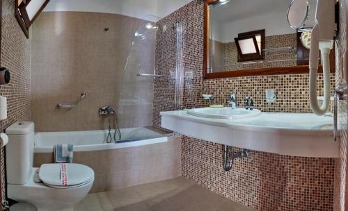 a bathroom with a tub and a sink and a toilet at HOTEL VICKY II in Plomari