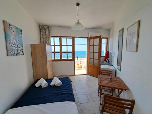 een slaapkamer met een bed en een tafel met uitzicht op de oceaan bij Nettuno Seafront Apartments in Análipsis