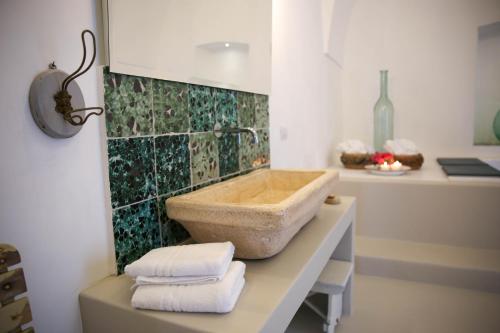 a bathroom with a stone tub on a counter with towels at Masseria Parco della Grava in Pezze di Greco