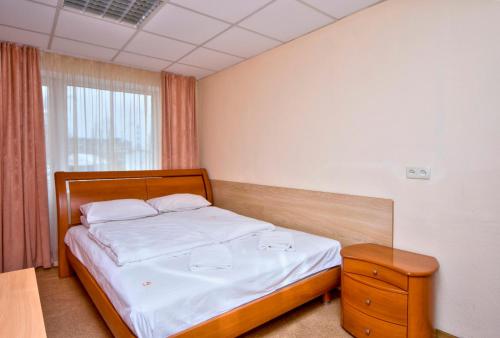 a bedroom with a bed with a wooden headboard and a window at Podolski Hostel in Kyiv