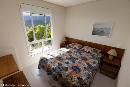 una camera da letto con un letto e una grande finestra di D21 - Conforto junto a natureza - Praia de Camburyzinho a São Sebastião