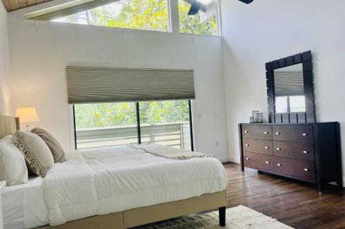a bedroom with a bed and a dresser and two windows at Magnolias on Cobblestone in Wesley Chapel