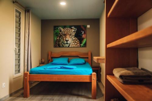 1 dormitorio con 1 cama con una pintura de tigre en la pared en Palma Lodges, en Kourou