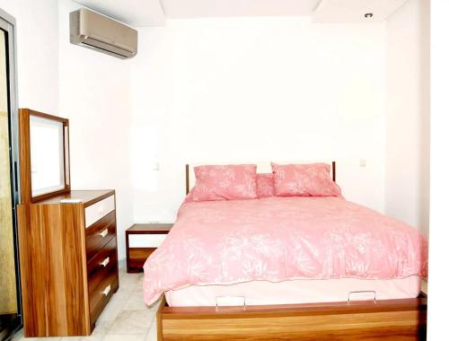 um quarto com uma cama com lençóis cor-de-rosa e um espelho em Beverly Hills California em Kenitra