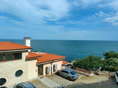 a house with a car parked in front of the ocean at Apartment Sunny in Casa Del Mare in Varna City