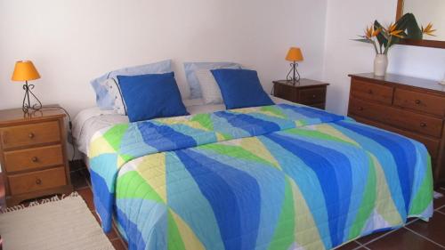 アレイア・ブランカにあるA Casinhaのベッドルーム1室(カラフルなベッド1台、ドレッサー2台、ランプ付)