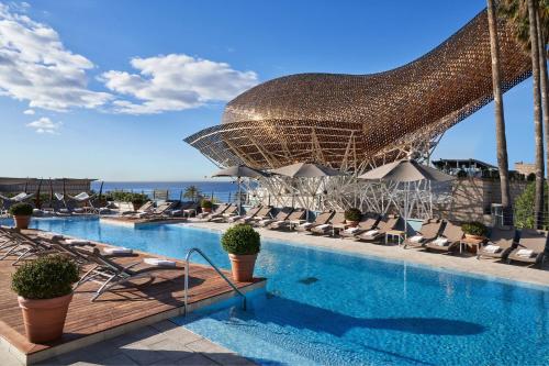 uma grande piscina com cadeiras e um grande guarda-sol em Hotel Arts Barcelona em Barcelona