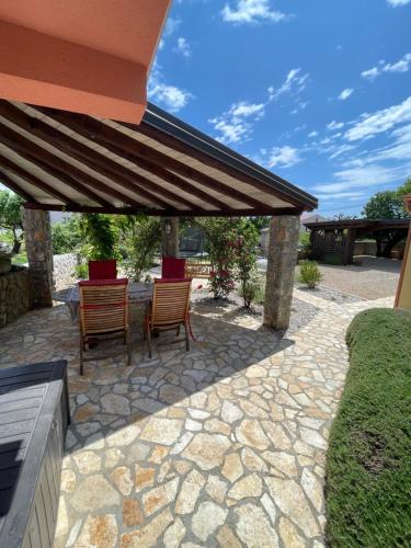 a patio with a table and chairs under an umbrella at Krk Houses in Kornić