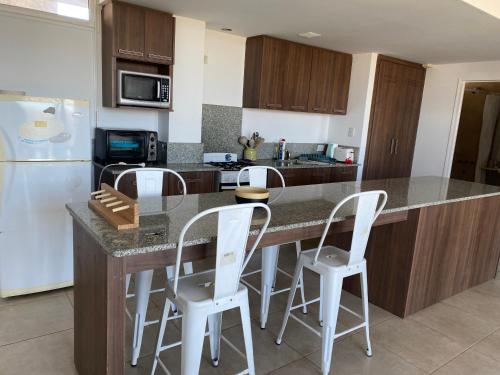 a kitchen with a counter with white stools in it at Pinto 32 in Tandil