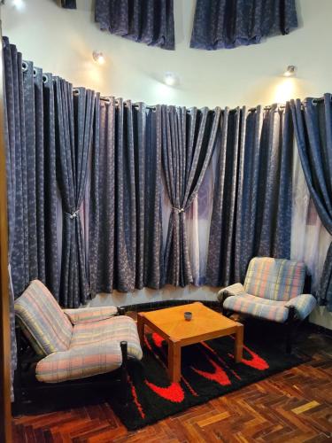 two chairs and a table in a room with curtains at Edaala Comfort - B&B in Nairobi