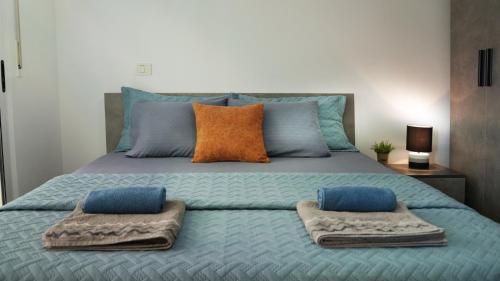 un letto con cuscini blu e asciugamani di High-Tech flat a Durrës