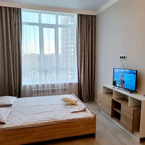 - une chambre avec un lit, une télévision et une fenêtre dans l'établissement Cozy 1 BR in the heart of Astana, à Astana