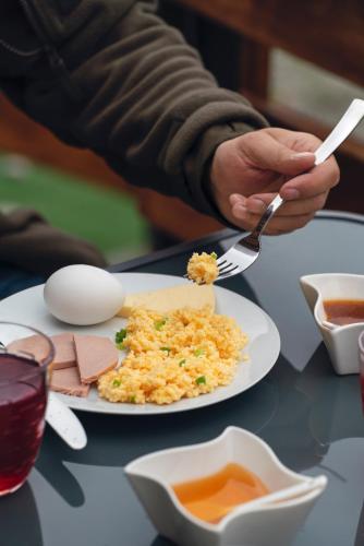 a person holding a fork and knife and a plate of food at Panorama Ushba in Mestia