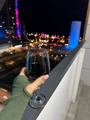a person holding a glass of wine on a ledge at Moonlight Apart-Hotel Batumi in Batumi