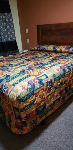 a bed with a colorful quilt on it in a room at Economy Inn Odessa in Odessa