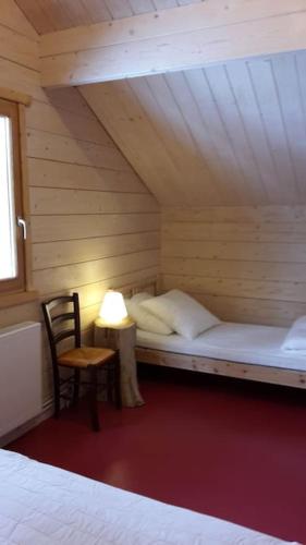 Cette chambre comprend un lit, une chaise et une lampe. dans l'établissement Chalet le Brame en Cevennes, à Camprieu