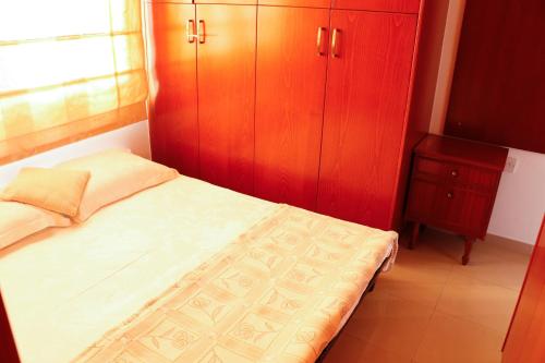 a small bedroom with a bed and wooden cabinets at Luxury Apartment, near Pinikoudes beach in Larnaka