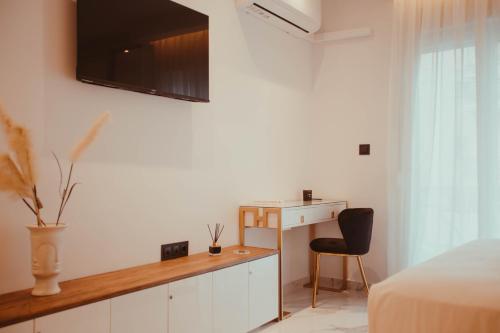 Aelia - Luxury Central Suite في أليكساندروبولي: غرفة نوم مع مكتب وتلفزيون على الحائط