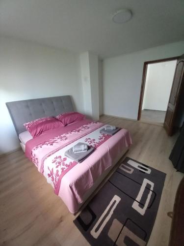 a bedroom with a bed with pink sheets and a rug at Apartman Deni in Tuzla