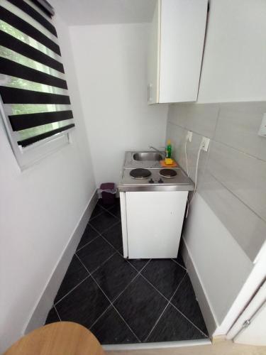 a small kitchen with a sink and a stove at Apartman Deni in Tuzla
