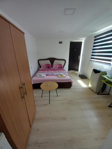 a room with a bed and a table in it at Apartman Deni in Tuzla