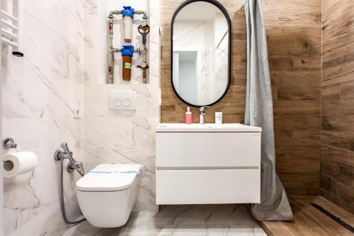 a white bathroom with a sink and a mirror at VIP Apartments in Lviv