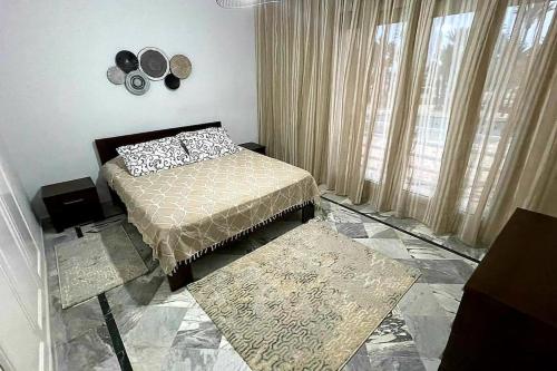 Schlafzimmer mit einem Bett und einem Fenster mit Vorhängen in der Unterkunft Appartement en bord de mer in Monastir