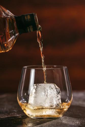 a person pouring whiskey into a glass at Panorama Ushba in Mestia