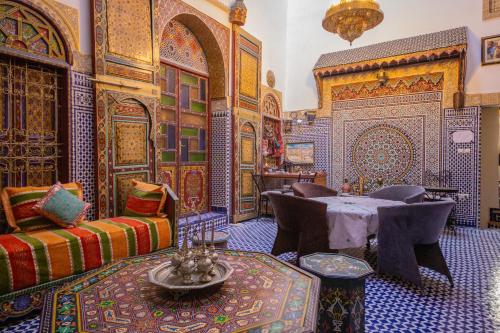 a living room with a table and chairs in a room with colorful tiles at Riad Fes Hayat in Fez