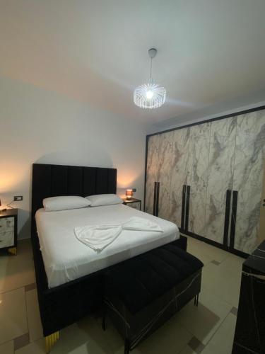 um quarto com uma cama grande e um lustre em Xh&S apartment em Durrës