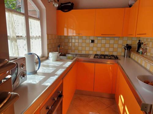 uma cozinha com armários laranja e um lavatório em Casa Piccolo Paradiso em Giuncarico