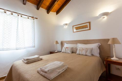 een slaapkamer met een bed met twee handdoeken erop bij Casa Ardomar in Carrapateira