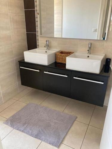 La salle de bains est pourvue de 2 lavabos, d'un miroir et d'un tapis. dans l'établissement Olympe de Provence, à Caromb