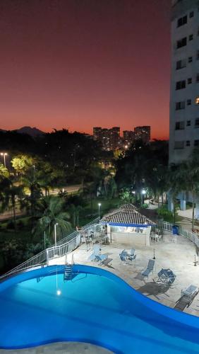 a large blue swimming pool with a city in the background at Apartamento Vila DR - Barra da Tijuca,prox Jeunesse,Arenas,Rio Centro,praias, Shopping in Rio de Janeiro