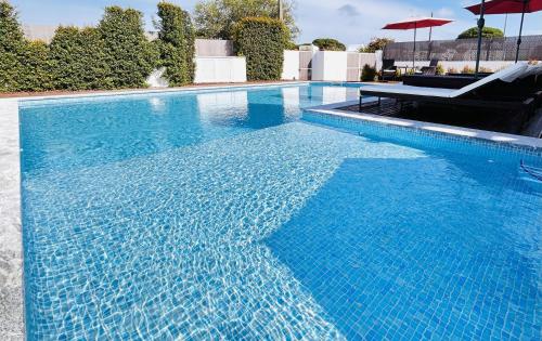 a large blue swimming pool with a table and umbrella at Romã do Meco in Aldeia do Meco