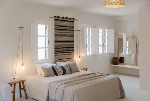 a white bedroom with a large bed and two windows at Scorpios Beach in Monolithos