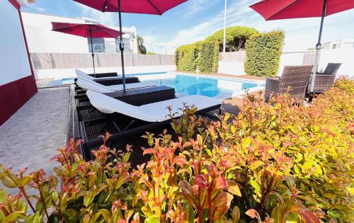 a swimming pool with two umbrellas and a bed and a pool at Romã do Meco in Aldeia do Meco