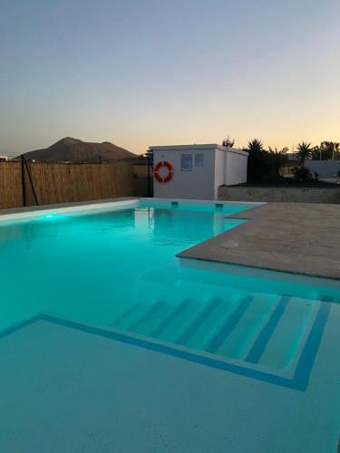a swimming pool with blue water in a backyard at Villa Verano Apartamentos Compartidos Villaverde in La Oliva