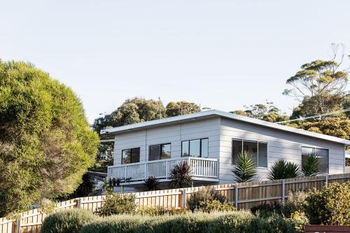 a house on a hill with a fence at Driftwood Rest Binalong Bay Sleeps 4 in Binalong Bay