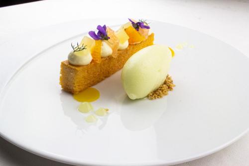 a piece of cake on a white plate with ice cream at Chateau d'Origny, Chambres d'hotes et Restaurant Gastronomique in Ouches