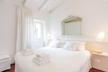 una camera da letto bianca con un letto e asciugamani di Di punto in bianco home a Verona