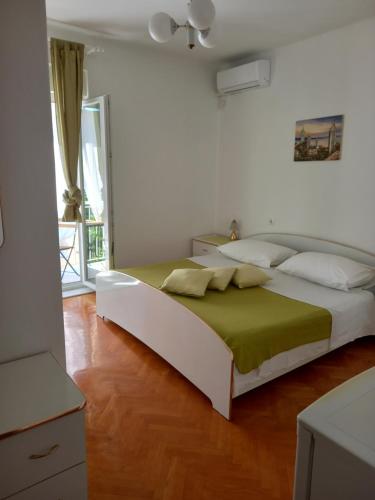 a bedroom with a white bed with a green blanket at SOBE ŠOTIĆ in Rab