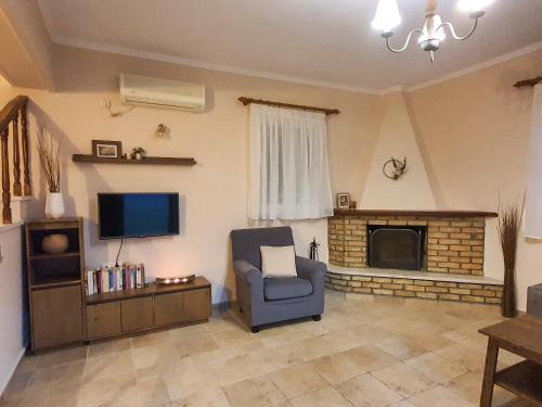 a living room with a chair and a television at Villa Ioanna in Kalamitsi